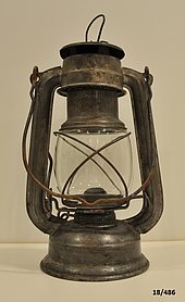Fotoaufnahme einer Laterne aus Blech und Glas, die mit Petroleum betrieben wird.