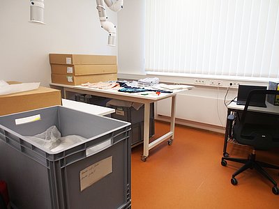 In der Werkstatt sind große Tische. Sie sind für Textilien. Darüber ist eine Absauganlage. Sie saugt den Staub ein.