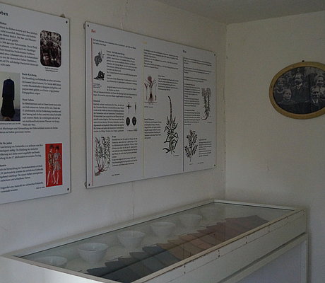 Ausstellungsvitrine mit gefärbten Stoffen und Texttafeln