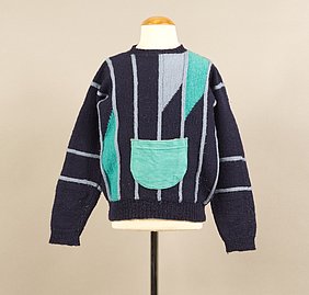 Der Pullover ist dunbkelblau. Er hat blaugraue Streifen. Zwei Stellen sind türkis. Vorne ist eine türkise Tasche aufgenäht.