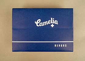 Die Packung ist blau. Auf ihr steht "Camelia". Die Schrift ist weiß. In der Packung sind Damenbinden.