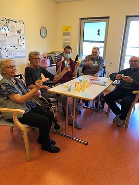 Senior/innen fertigen mit ihrer Betreuung Tauben aus Papier