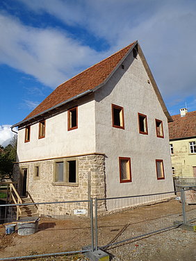 Schräge Aufsicht auf die östliche und südliche Seite der Synagoge. Bau ist auf der einen Seite voll verputzt, auf der anderen Seite nur im 1. Stock.