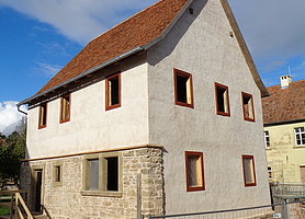 Schräge Aufsicht auf die östliche und südliche Seite der Synagoge. Bau ist auf der einen Seite voll verputzt, auf der anderen Seite nur im 1. Stock.