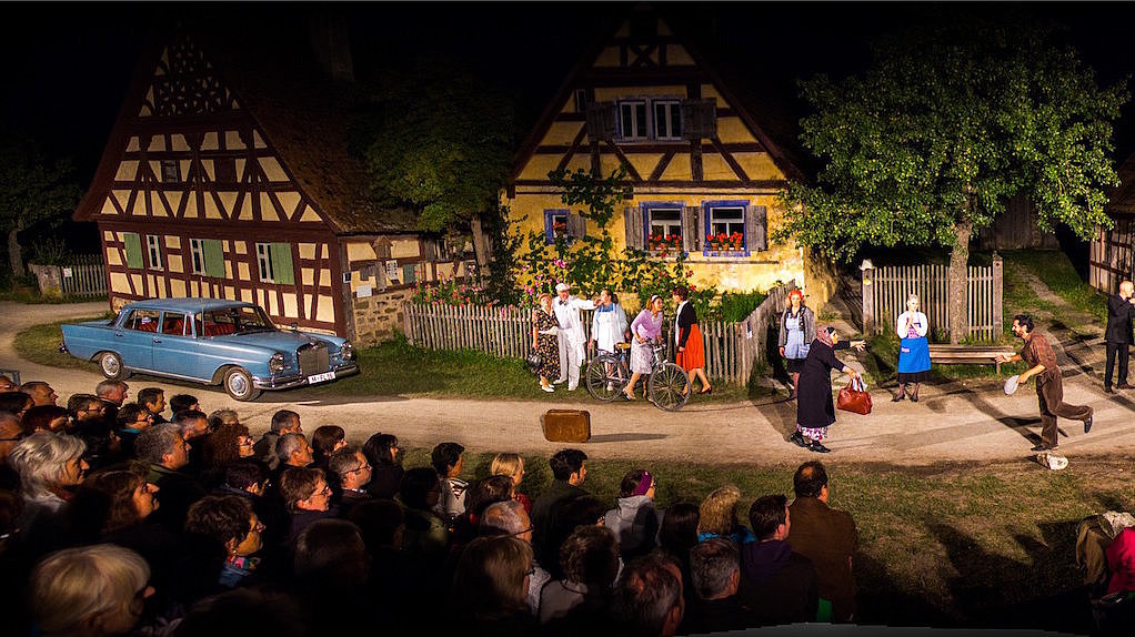 Theaterszene vor drei Häusern des Freilandmuseums
