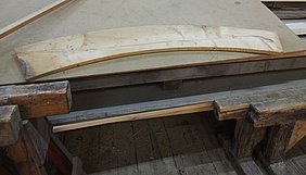 Eine Schablone aus Holz in der Form eines Segments dient als Vorlage für die 36 Segmente der vier Felgen – jeder Radkranz besteht aus zwei Felgen.