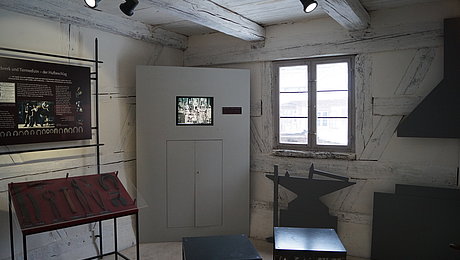 Videostation und Ausstellungsvitrine mit Eisenzangen und Hammer