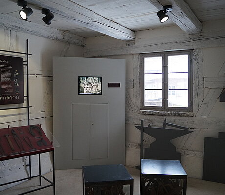 Videostation und Ausstellungsvitrine mit Eisenzangen und Hammer 