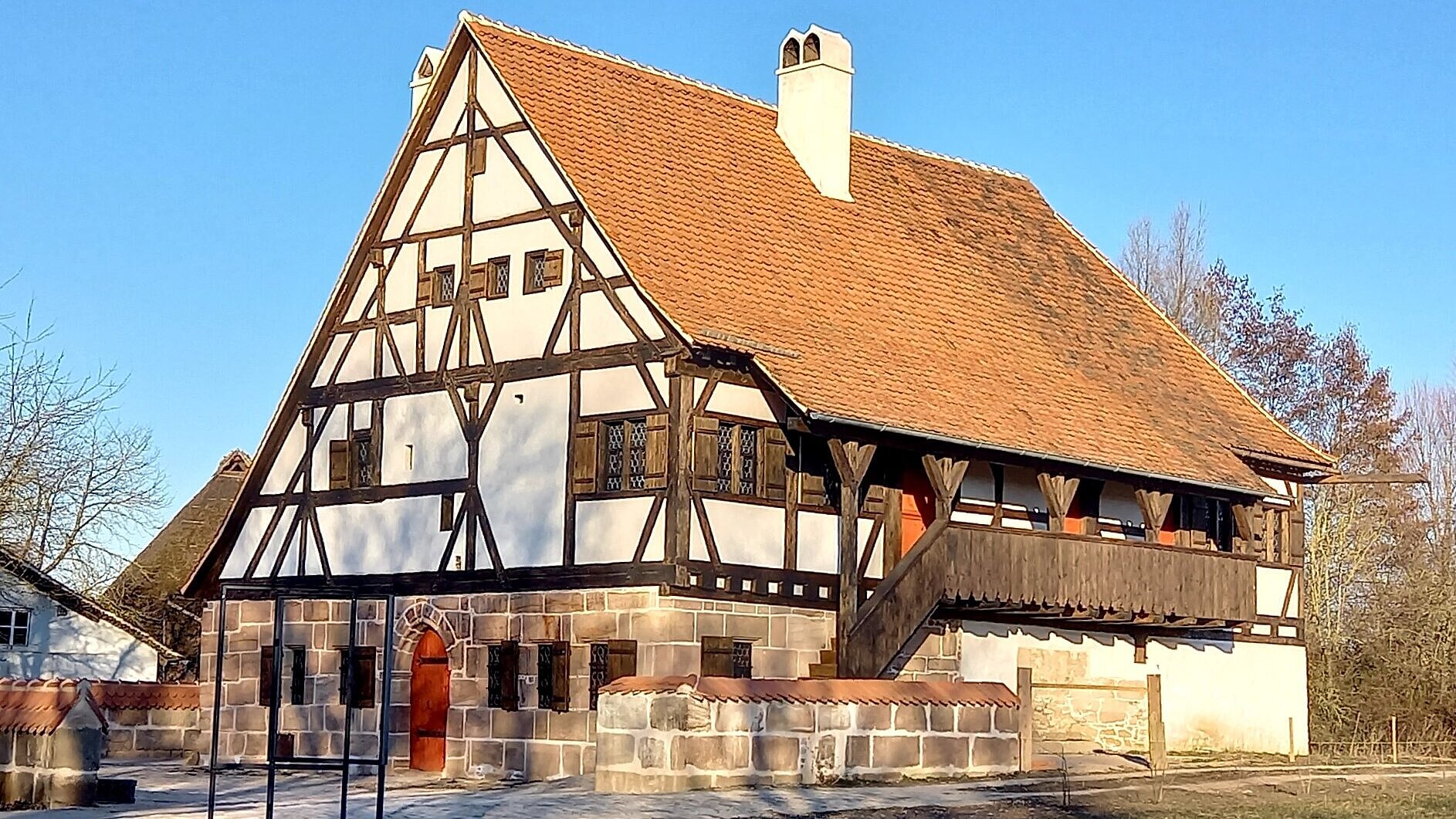 Das Badhaus ist ein Fachwerkhaus. Das Fachwerk ist dunkel. Die Gefache sind weiß. Das Dach ist rot. Das Erdgeschoss ist aus Sandsteinen.