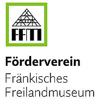 Abbildung des Logos des Fördervereins Fränkisches Freilandmuseum e.V., der Name steht in der unteren Hälfte. In einem rechteckigen Rahmen darüber stellen die Abkürzung „FFM“ und ein gezeichneter Fachwerkgiebel ein Haus dar.