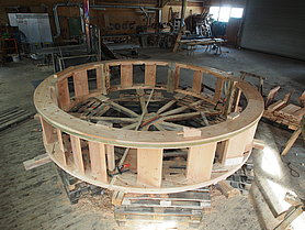 Das Mühlrad ist mit den bisher fertig gestellten Teilen auf dem Lehrgerüst grob aufgebaut: Jeweils zwei Felgenringe bilden einen Radkranz. Zwischen den beiden Radkränzen sind die Schaufelhölzer eingepasst. Die Kopfhölzer sitzen an den Positionen, wo später die Speichen eingepasst werden.