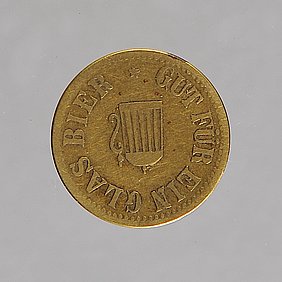 Die Marke ist eine Münze. Sie ist goldfarben. Auf ihr ist ein Bierkrug.