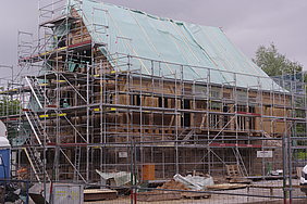 das voll eingerüstete Badhaus, noch mit grüner Plastikplane auf dem Dach