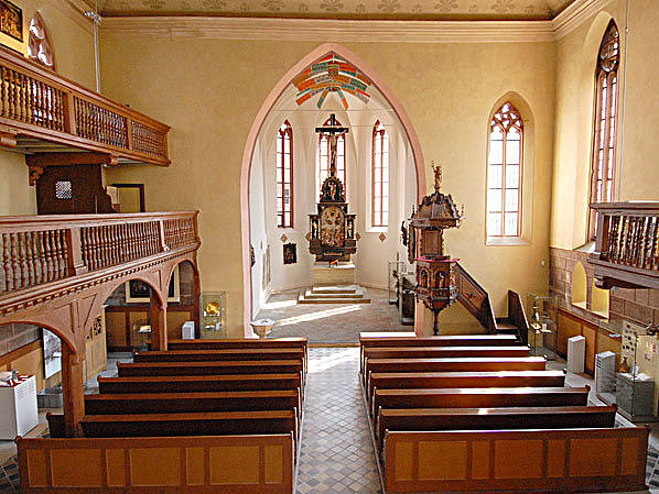 FFM_Museum_Kirche_Franken Fotoaufnahme des Innenraums der Spitalkirche mit den beiden Emporen. Der Altar befindet sich mittig im Kirchenschiff, rechts steht die erhöhte Kanzel. Davor sind einige Reihen mit Bänken.