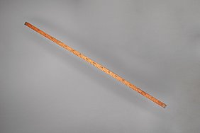 Der Stab ist genau einen Meter lang. Auf ihm sind Zahlen und Striche. Mit dem Stab kann man messen.
