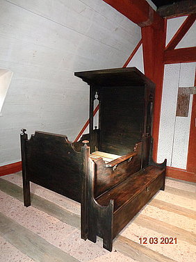 FFM_Badhaus_Wendelstein_Himmelbett u. Truhe Himmelbett, daneben eine Truhe in einem Raum mit Dachschräge