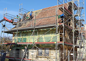 Eingerüstete Synagog aus Allersheim mit Dachdeckern am Werk