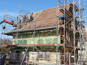 Eingerüstete Synagog aus Allersheim mit Dachdeckern am Werk