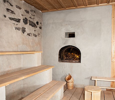 Ausstellung_Badhaus_Wendelstein_Schwitzstube gestaffelte Bänke (wie in einer Sauna) vor einem offenen Holzofen