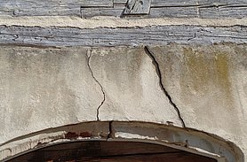In der Mauer sind zwei Risse. Sie sind über der Tür.