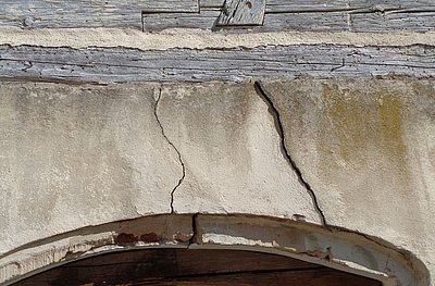 In der Mauer sind zwei Risse. Sie sind über der Tür.