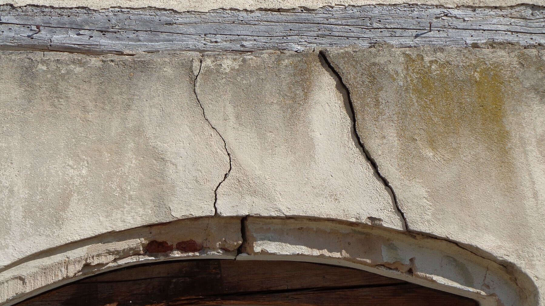In der Mauer sind zwei Risse. Sie sind über der Tür.