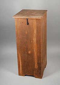 Die Wahlurne ist ein Kasten aus Holz. Im Deckel ist ein Schlitz. Der Kasten kann verschlossen werden.