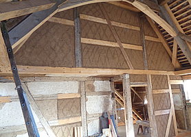 Bogenförmige Holzkonstruktion vor hoher Fachwerkwand. Innenansicht des Betsaals
