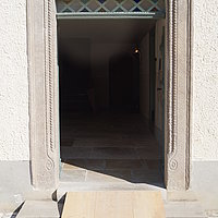 FFM_Haupteingang_Reichersdorf Fotoaufnahme des Haupteingangs vom Bauernhaus aus Reichersdorf. Zur Tür führen zwei Steinstufen, über diese wurde eine Rampe aus Holz gelegt. Der Boden des Hofs ist gepflastert, der des Hauses gefliest.