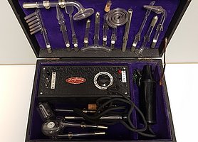 Ein schwarzer, aufgeklappter Koffer, gefüllt mit einem schwarzen kastenförmigen Messgerät mit Kabel und zahlreichen Aufsätzen aus Glas 