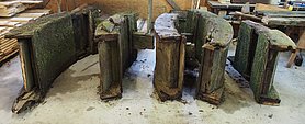 1)	Das kaputte Mühlrad wurde beim Abbau in vier gleichgroße Segmente zerlegt. Sie lagern in der Abbundhalle des Bauhofs.