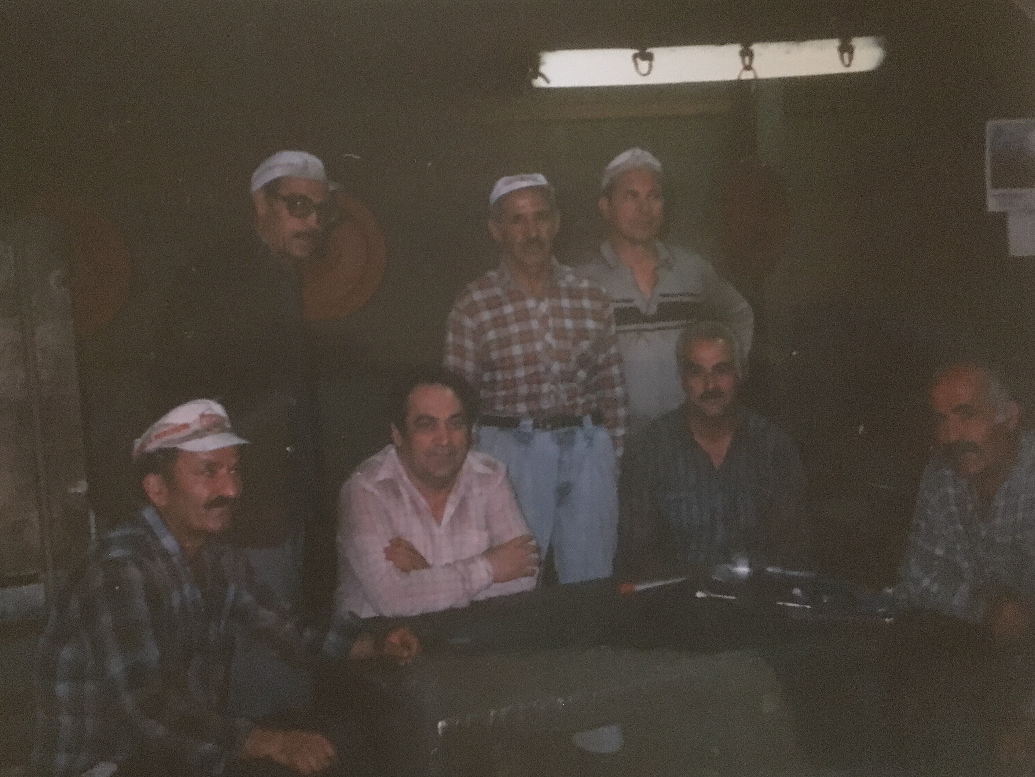 Die Männer sind in einer Fabrik. Sie machen Pause. Sie stammen aus der Türkei. Sie leben und arbeiten in Deutschland.