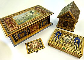 Die Schachteln sind braun und teilweise bemalt. Auf ihnen befinden sich Muster aus Stroh.
