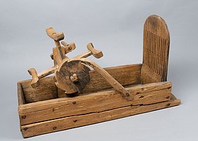 Der Bandwebstuhl von der Seite. Das Rad hat an der Seite ein Sternmuster.