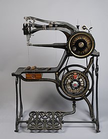 Die Nähmaschine ist schwarz und aus Eisen. Sie wird mit einem Fußpedal angetrieben. Oben ist ein Arm, aus dem Nadel und Faden herauskommen. Darunter ist ein anderer Arm. Auf dem kann das Leder zum Nähen abgelegt werden. Die Maschine hat auch eine kleine Schublade.