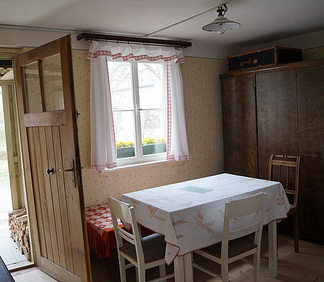 Die Stube des Behelfsheimes mit Tisch, Stühlen und großem Kleiderschrank