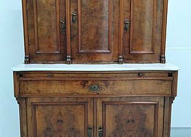 Das Wohnzimmerbuffet ist ein Schrank. Er besteht aus einem Unterschrank und einem Aufsatz. Der Aufsatz ist oben bogenförmig.