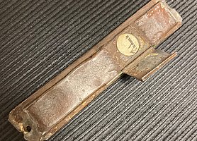 Die Mesusa ist eine kleine Schachtel. Sie ist länglich und aus Messing. Sie enthält eine Schriftrolle aus Pergament. Ein hebräischer Buchstabe ist zu sehen.