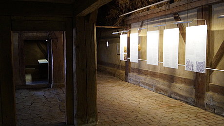 Texttaflen und mächtige Holzsäule im Inneren des Bauernhauses