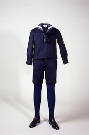 Der Anzug ist blau. Das Hemd ist blau und hat weiße Streifen am Kragen. Die blaue Hose ist kurz.