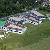Fotoaufnahme des evangelischen Schullandheims aus der Vogelperspektive. Gezeigt werden fünf Gebäude mit Flachdach, daneben ist ein Sportplatz mit Fußballtoren. Das Schullandheim befindet sich in der Nähe vom Museumseingang. 