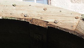 Das Foto zeigt ein Radkranzdetail des alten Rades: Die Zapfen der Schaufeln und die Holznägel sitzen in der Felge.