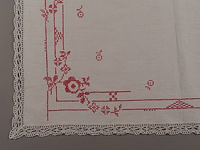 Auf der Altardecke sind rote Stickereien. Sie zeigen Blüten und Knospen von Rosen.