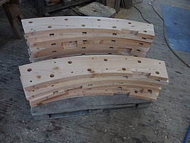 Die 19 Segmente des ersten Radkranzes sind fertig, sie sind auf einer Palette aufgestapelt. Sie sind mit der Verbindung für die Kopfhölzer, sowie mit den Zapfen- und Holznagellöchern versehen.