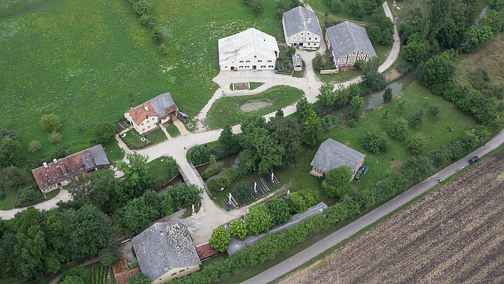 FFM_Altmühlfranken_Luftaufnahme Fotoaufnahme eines Luftbildes der Baugruppe Süd. Das Bild wurde von Süden aus aufgenommen. Die einzelnen Gebäude sind durch Wege miteinander verbunden. Umliegend befinden sich Felder, Wiesen und Bäume.