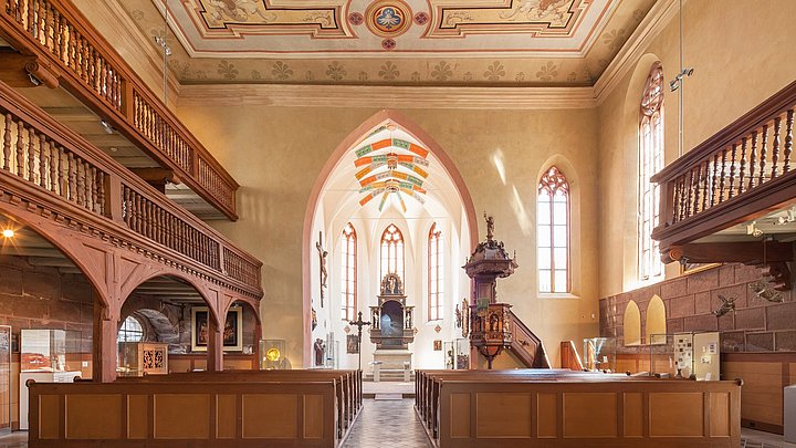 FFM_Spitalkirche1 Fotoaufnahme des Innenraums der Spitalkirche von hinten. Im Vordergrund befinden sich mehrere Reihen mit Sitzbänken. An den Seiten ziehen sich Emporen mit verzierten Holzgeländer entlang. Im Hintergrund sind die hölzerne Kanzel und der Altar erkennbar.