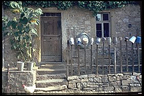 „Milchtöpfe“ und auch der kleine Bierkrug aus Steingut trocknen auf dem Zaun vor dem Haus; Mainstockheim 1964, Foto Otto Beck im Bildarchiv des Fränkischen Freilandmuseums Steinhaus mit Zaun an dem Gefäße hängen.