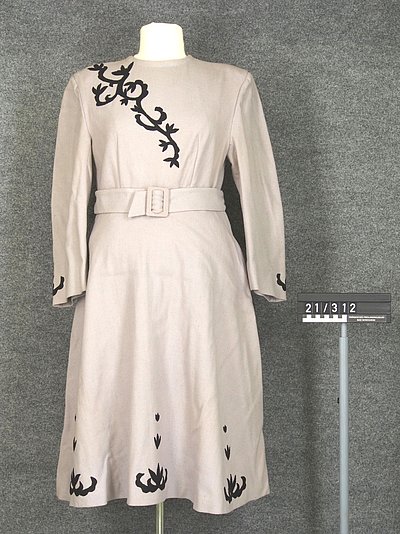Das Winterkleid ist weiß. Auf der Brust ist ein schwarzer Zweig. Unten sind Blätter. Um die Taille ist ein Band.