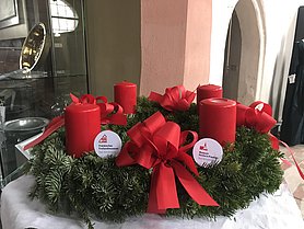 Adventskranz mit roten Kerzen und roten Schleifen