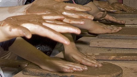 FFM_Ziegelwerkstatt_Haende Kinderhände, die aus Ton Ziegel formen bzw. schlagen mittels eines Metalrahmens